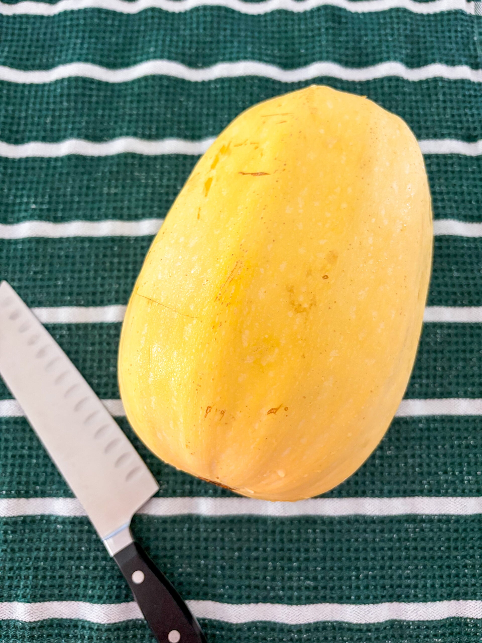 Spaghetti squash on dish towel next to chef's knife