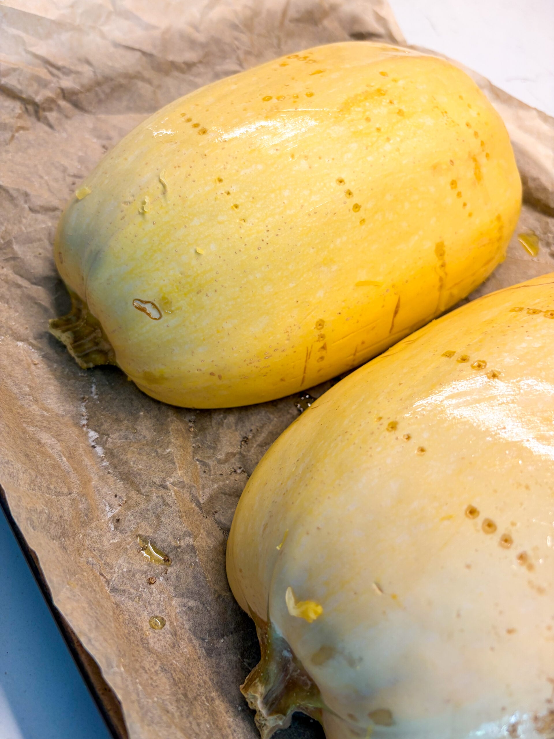 Spaghetti squash halves cut-side down on parchment lined baking sheet